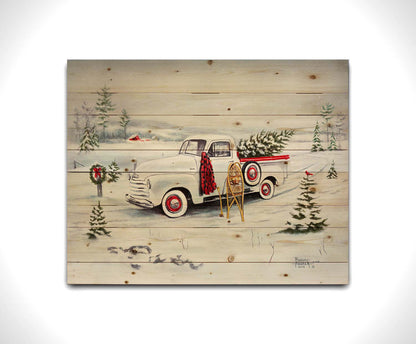 A painting of a vintage white truck in the snow, carrying a snow-covered evergreen tree. Printed on a wood pallet.