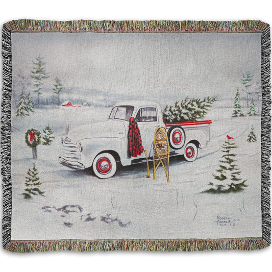 Woven blanket with a truck and Christmas tree design.