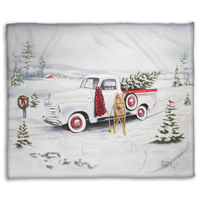 Festive blanket with a vintage truck and Christmas trees design.