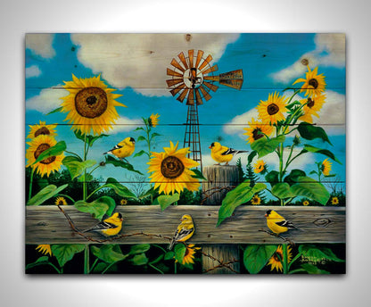 A painting of a field of sunflowers and yellow American Goldfinches, also known as chickadees. The sky is a vibrant blue, and a windmill sits in the background. Printed on a wood pallet.