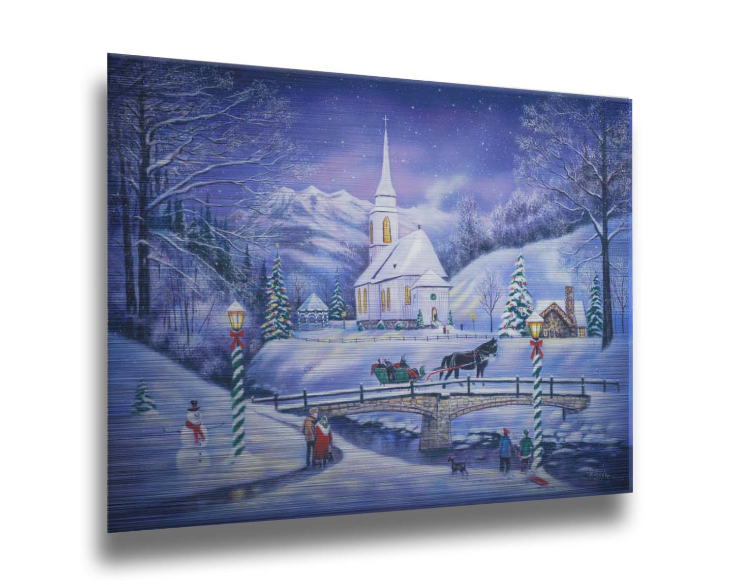 A painting of a snowy mountain town, decorated for Christmas. A tall church sits in the middle of town. A horse-drawn sleigh crosses a bridge over a freezing river. Printed on metal.