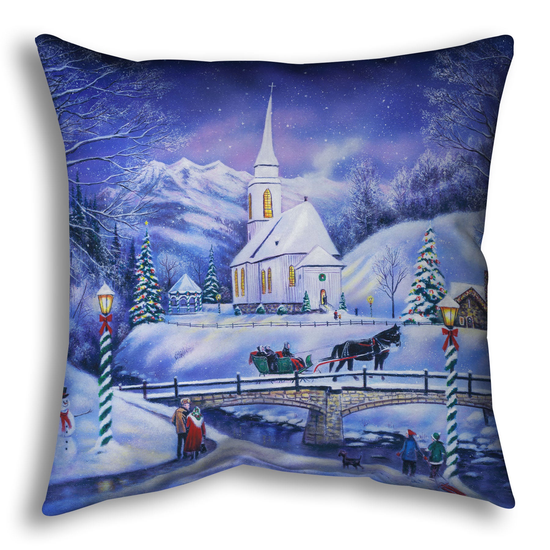 A throw pillow designed with a snowy mountain town, decorated for Christmas. A tall church sits in the middle of town.