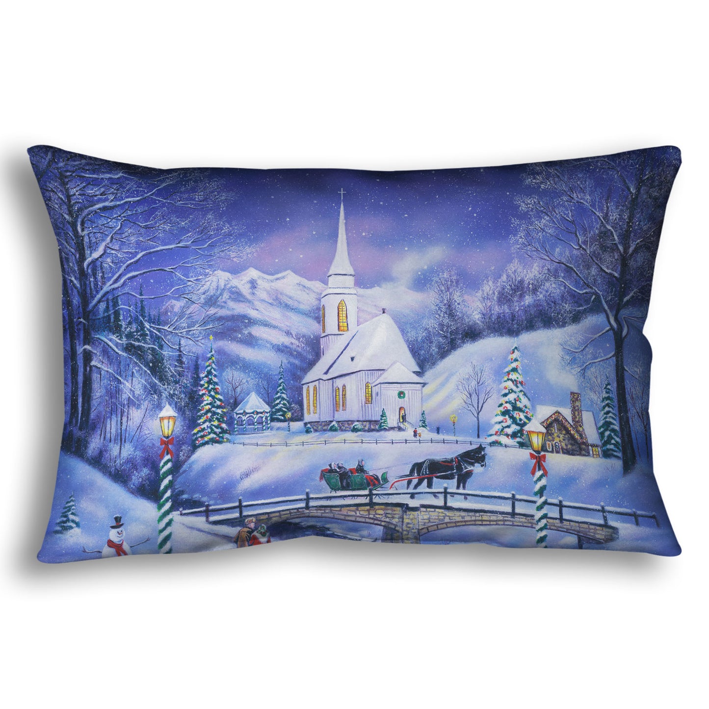 A throw pillow designed with a snowy mountain town, decorated for Christmas. A tall church sits in the middle of town.