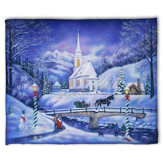 A coral fleece blanket designed with a snowy mountain town, decorated for Christmas. A tall church sits in the middle of town.
