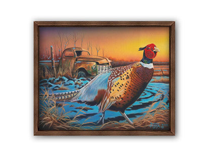 A painting of a pheasant trotting through a snowy field. In the background, an old green truck sits rusted. The sun is low in the sky, creating a soft orange atmosphere. Printed on canvas and framed.