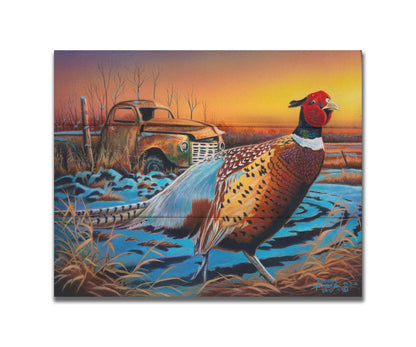 A painting of a pheasant trotting through a snowy field. In the background, an old green truck sits rusted. The sun is low in the sky, creating a soft orange atmosphere. Printed on a box board.