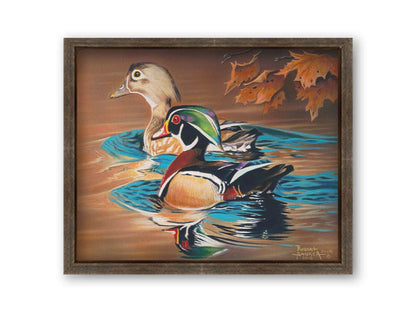 A painting of two wood ducks swimming through the water during fall. Their reflections are broken by the ripples of the water. Printed on canvas and framed.