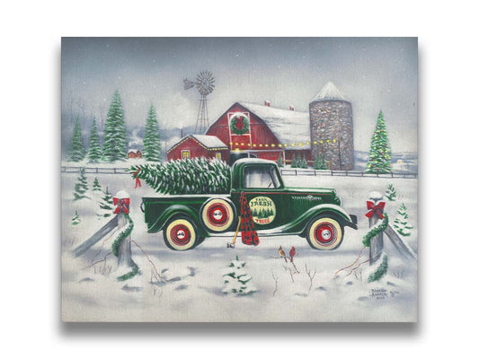 A painting of a green truck on a snowy road, preparing to deliver a freshly cut evergreen tree to a customer. A big red barn sits in the background, surrounded by large evergreens decorated for Christmas. Printed on canvas.