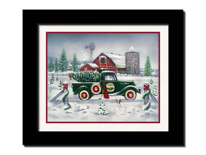 A painting of a green truck on a snowy road, preparing to deliver a freshly cut evergreen tree to a customer. A big red barn sits in the background, surrounded by large evergreens decorated for Christmas. Printed on paper, matted, and framed.