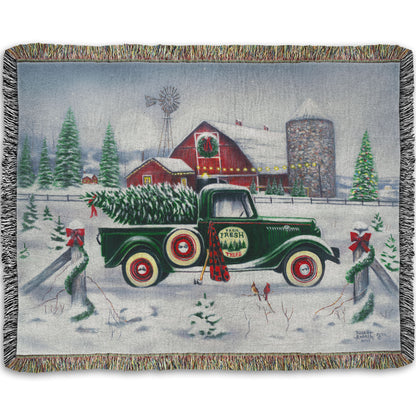 Woven blanket with a vintage truck and cabin design in a winter landscape.