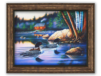 A painting of a family of loons swimming on a lake carrying their young. A pier extends to a cabin in the woods in the background. Printed on canvas and framed.