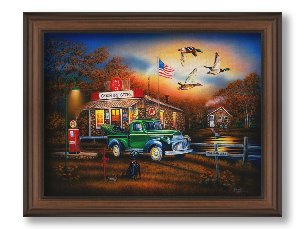 A painting of a "Country Store" and gas station, with a small house in the background. A small pond, with a sign reading "Mallard Lake," is beside it. A little green truck is parked in the front, carrying a green kayak. A black dog sits nearby, watching three mallard ducks fly overhead. Printed on canvas and framed.