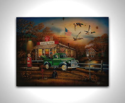 A painting of a "Country Store" and gas station, with a small house in the background. A small pond, with a sign reading "Mallard Lake," is beside it. A little green truck is parked in the front, carrying a green kayak. A black dog sits nearby, watching three mallard ducks fly overhead. Printed on a wood pallet.