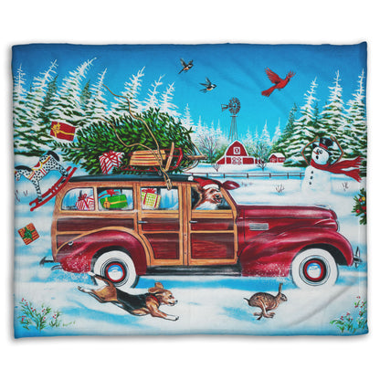 A coral fleece blanket printed with a festive Christmas painting, with a classic wood panel car speeding by with presents.