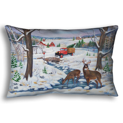 Festive throw pillow with winter scene featuring a vintage red truck carrying an evergreen for Christmas over a stream where deer drink.