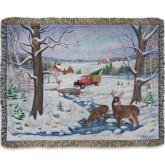 Festive blanket with winter scene featuring a vintage red truck carrying an evergreen for Christmas over a stream where deer drink.