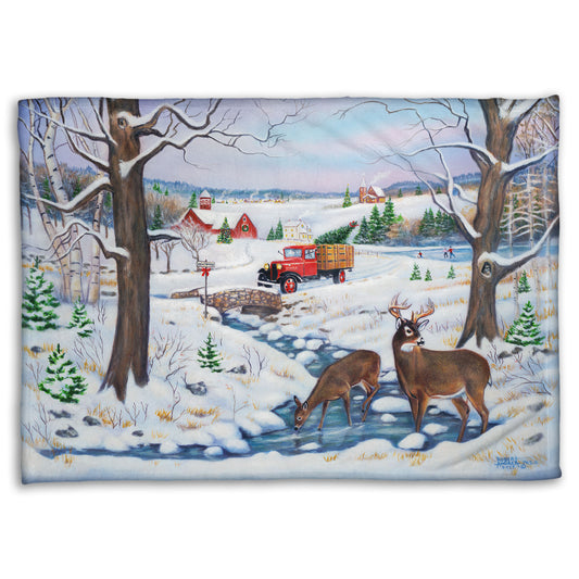 Festive blanket with winter scene featuring a vintage red truck carrying an evergreen for Christmas over a stream where deer drink.