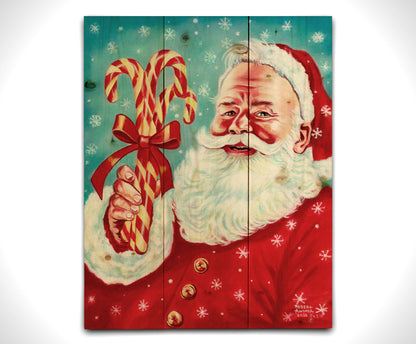 Illustrative painting of Santa Claus smiling and holding candy canes against a a blue snowing sky. Printed on a wood pallet.