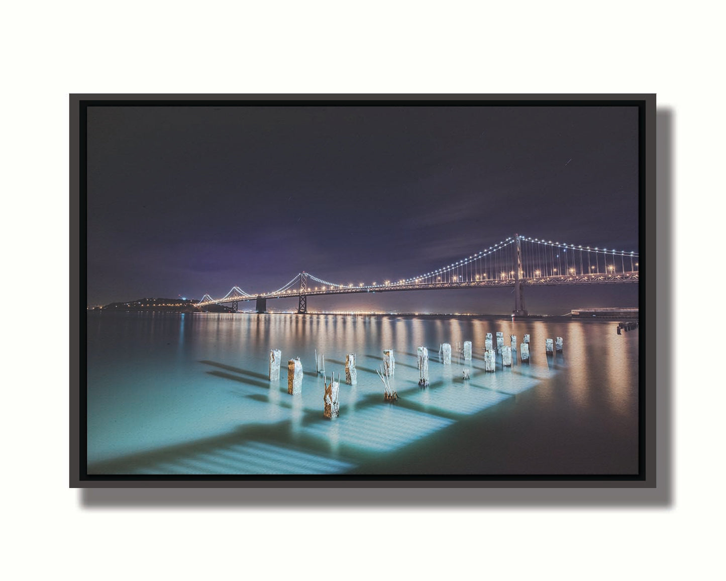 Photo of the Oakland Bay Bridge in San Francisco at night, taken from the Embarcadaro. Printed on canvas in a float frame.