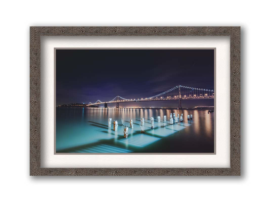 Photo of the Oakland Bay Bridge in San Francisco at night, taken from the Embarcadaro. Printed on paper, matted, and framed.