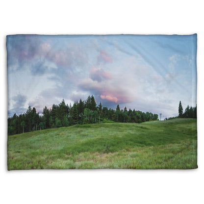 A coral fleece blanket designed with a photo of the hills and sky at Sundance in Utah, at the Provo Canyon by Mount Timpanogos.