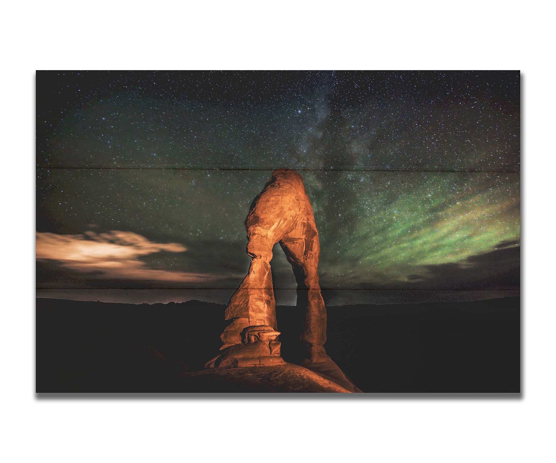 Nighttime photo of Delicate Arch in Arches National Park, Utah. The arch is lit with staged lighting, with a backdrop of a starry night sky. Printed on a box board.