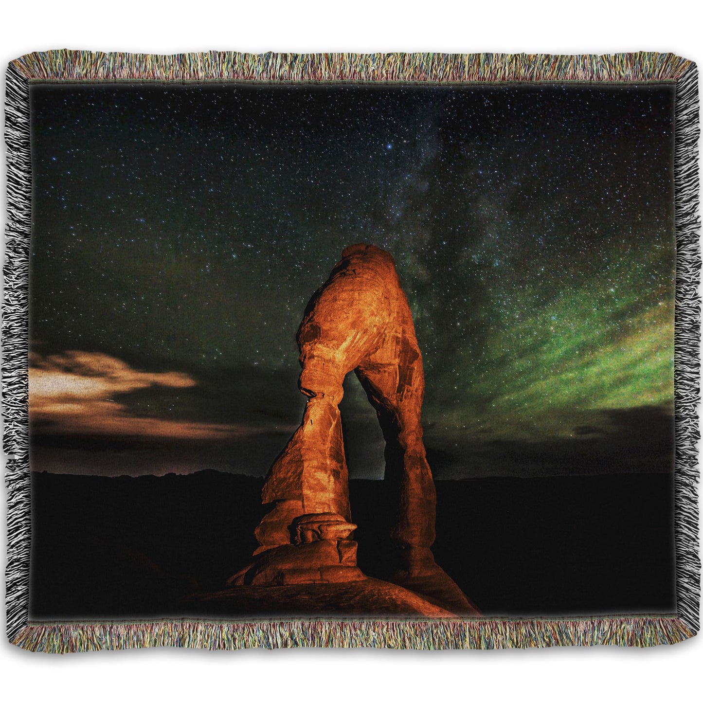 Woven throw blanket designed with a nighttime photo of Delicate Arch in Arches National Park, Utah. The arch is lit with staged lighting, with a backdrop of a starry night sky.