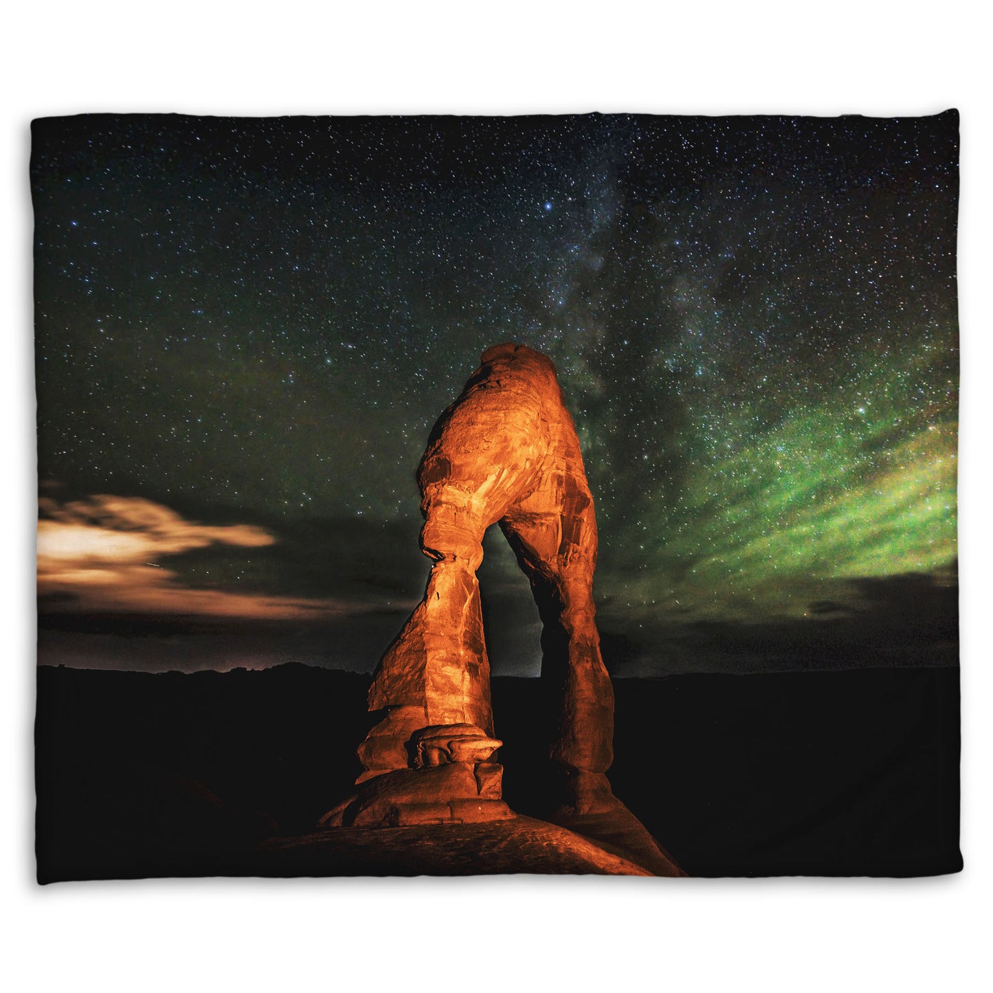 Coral fleece blanket designed with a nighttime photo of Delicate Arch in Arches National Park, Utah. The arch is lit with staged lighting, with a backdrop of a starry night sky.