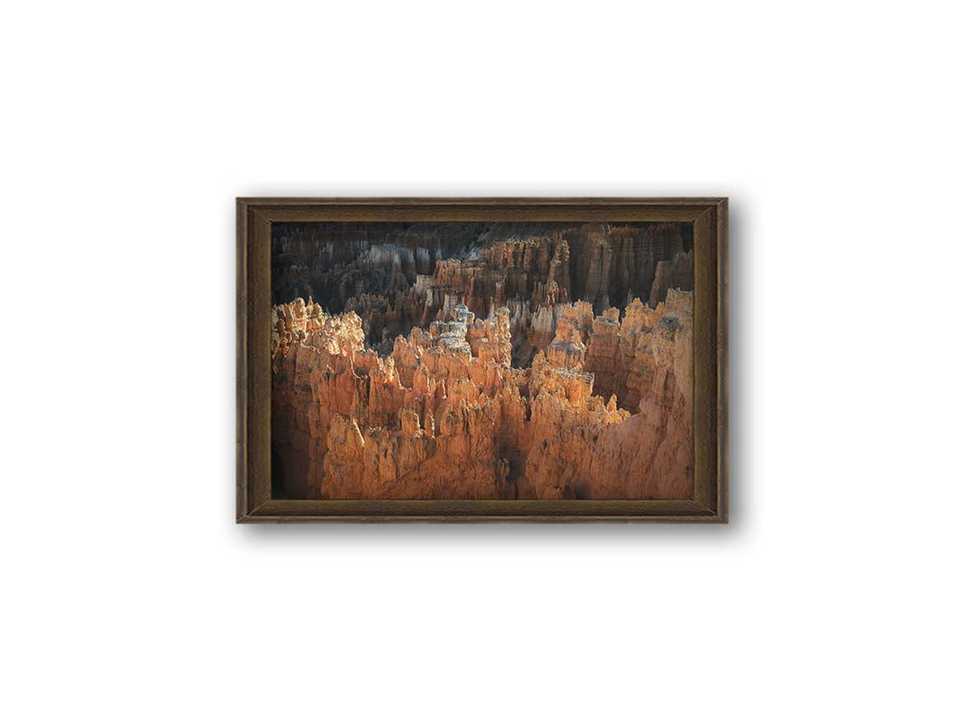 A photo of hoodoo rock formations, jagged stone spires formed by the erosion of a plateau, in Bryce Canyon National Park from a high angle. Printed on canvas and framed.