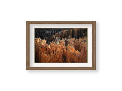 A photo of hoodoo rock formations, jagged stone spires formed by the erosion of a plateau, in Bryce Canyon National Park from a high angle. Printed on paper, matted, and framed.