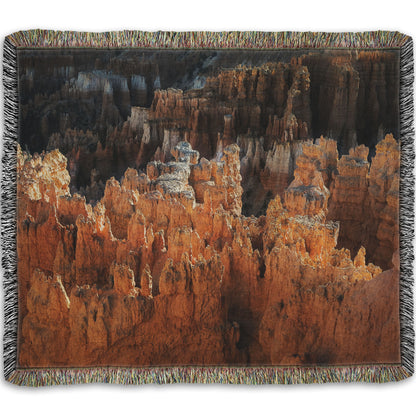 A woven blanket designed with a photo of hoodoo rock formations, jagged stone spires formed by the erosion of a plateau, in Bryce Canyon National Park from a high angle.