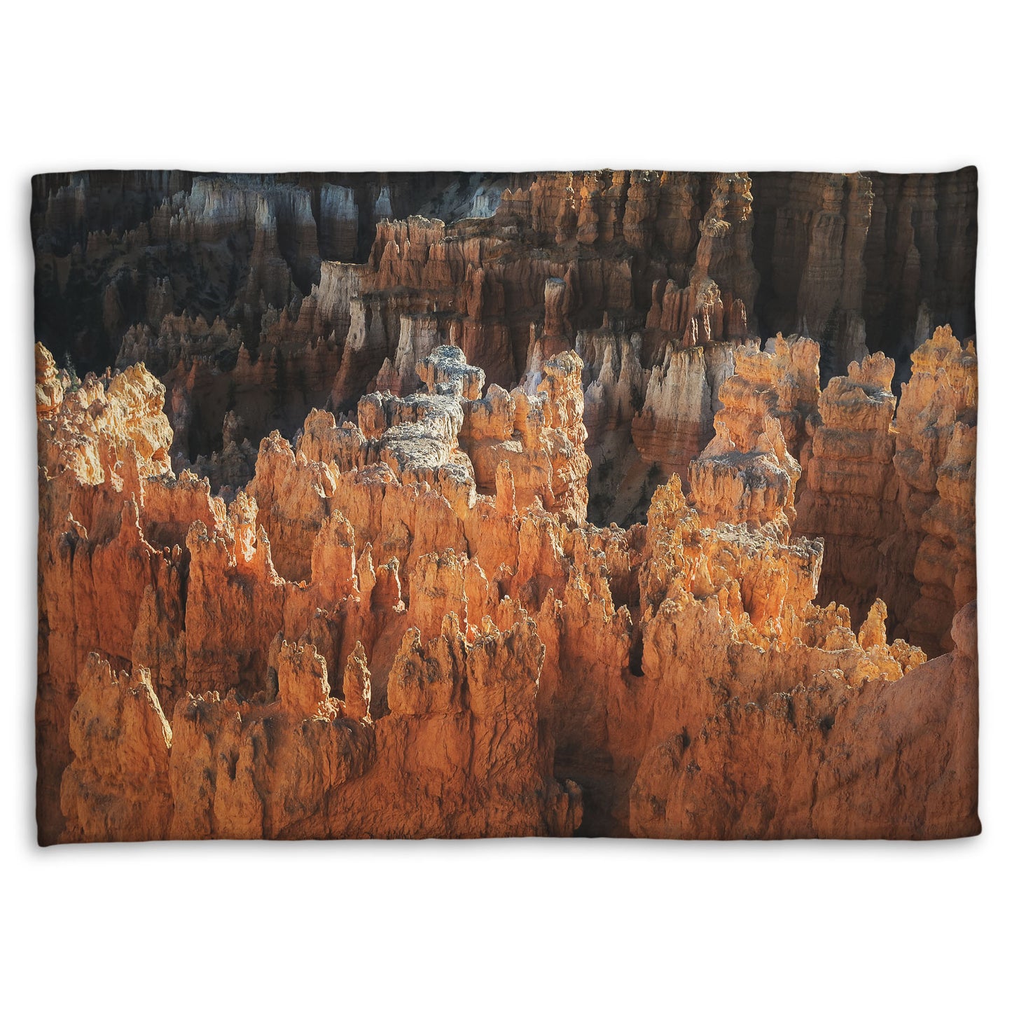 A fleece throw blanket designed with a photo of hoodoo rock formations, jagged stone spires formed by the erosion of a plateau, in Bryce Canyon National Park from a high angle.