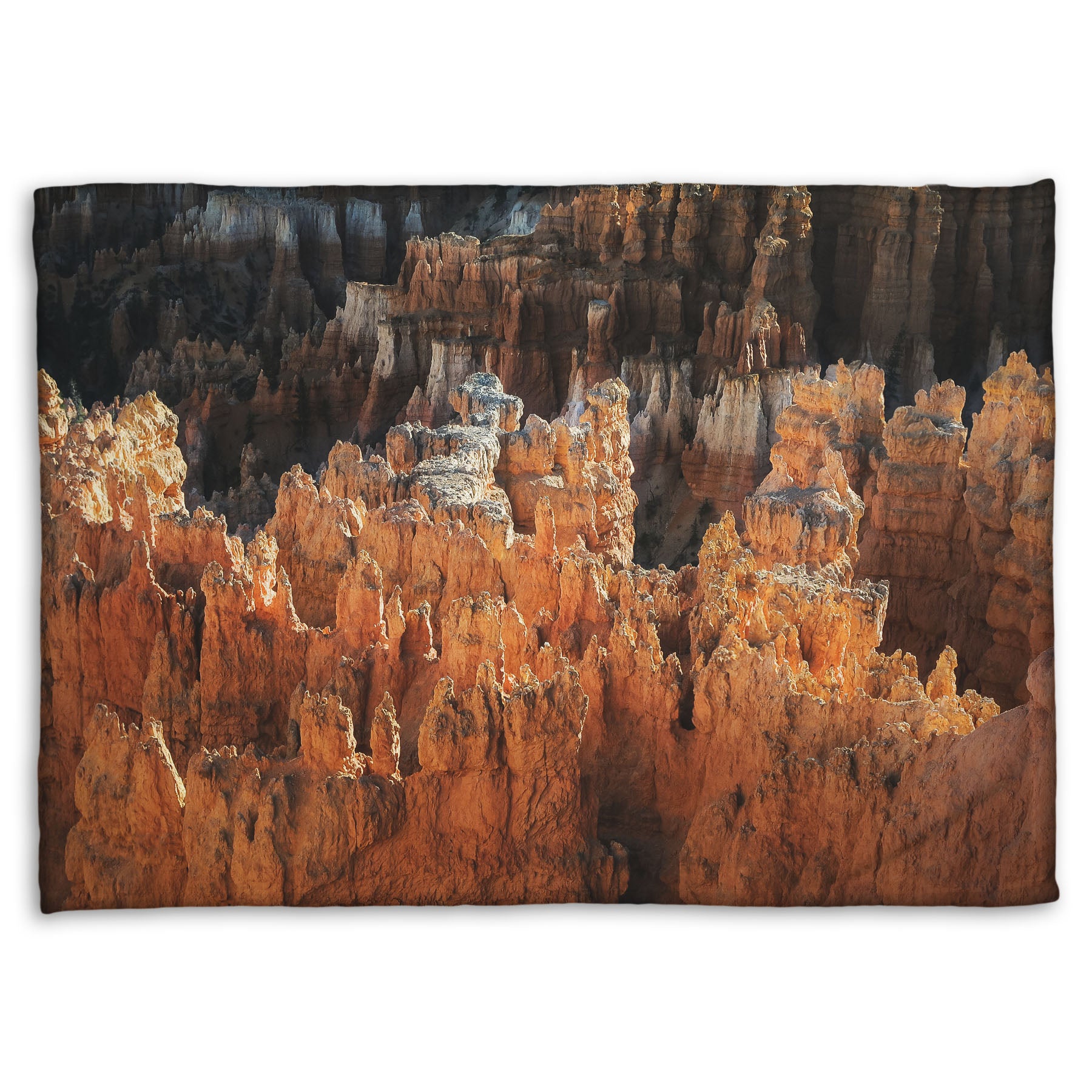 A fleece throw blanket designed with a photo of hoodoo rock formations, jagged stone spires formed by the erosion of a plateau, in Bryce Canyon National Park from a high angle.