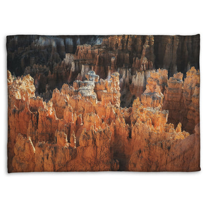 A fleece throw blanket designed with a photo of hoodoo rock formations, jagged stone spires formed by the erosion of a plateau, in Bryce Canyon National Park from a high angle.