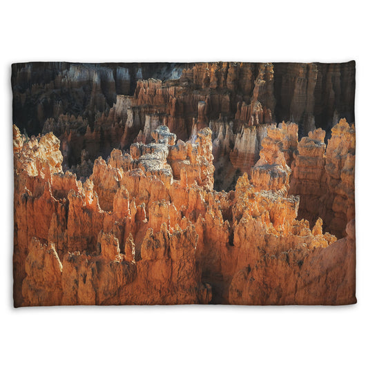 A fleece throw blanket designed with a photo of hoodoo rock formations, jagged stone spires formed by the erosion of a plateau, in Bryce Canyon National Park from a high angle.