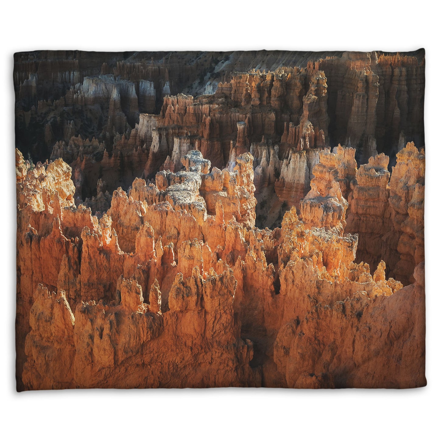 A fleece throw blanket designed with a photo of hoodoo rock formations, jagged stone spires formed by the erosion of a plateau, in Bryce Canyon National Park from a high angle.