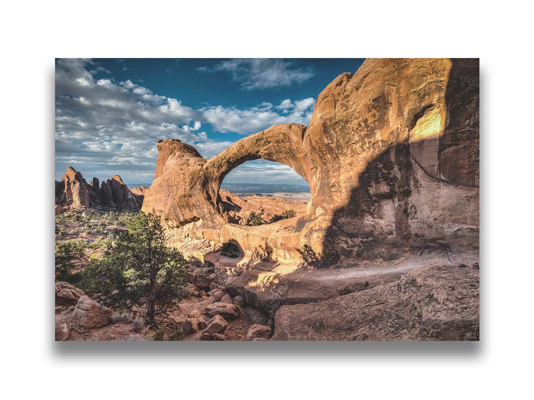 Photo of the Double O arch in the Devil's Garden at Arches National Park, Utah. The rocky arch is set against a bright blue sky. Printed on canvas.