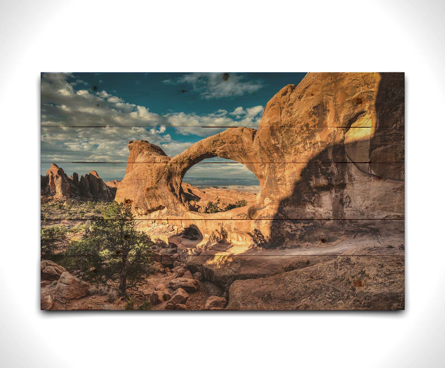 Photo of the Double O arch in the Devil's Garden at Arches National Park, Utah. The rocky arch is set against a bright blue sky. Printed on a wood pallet.