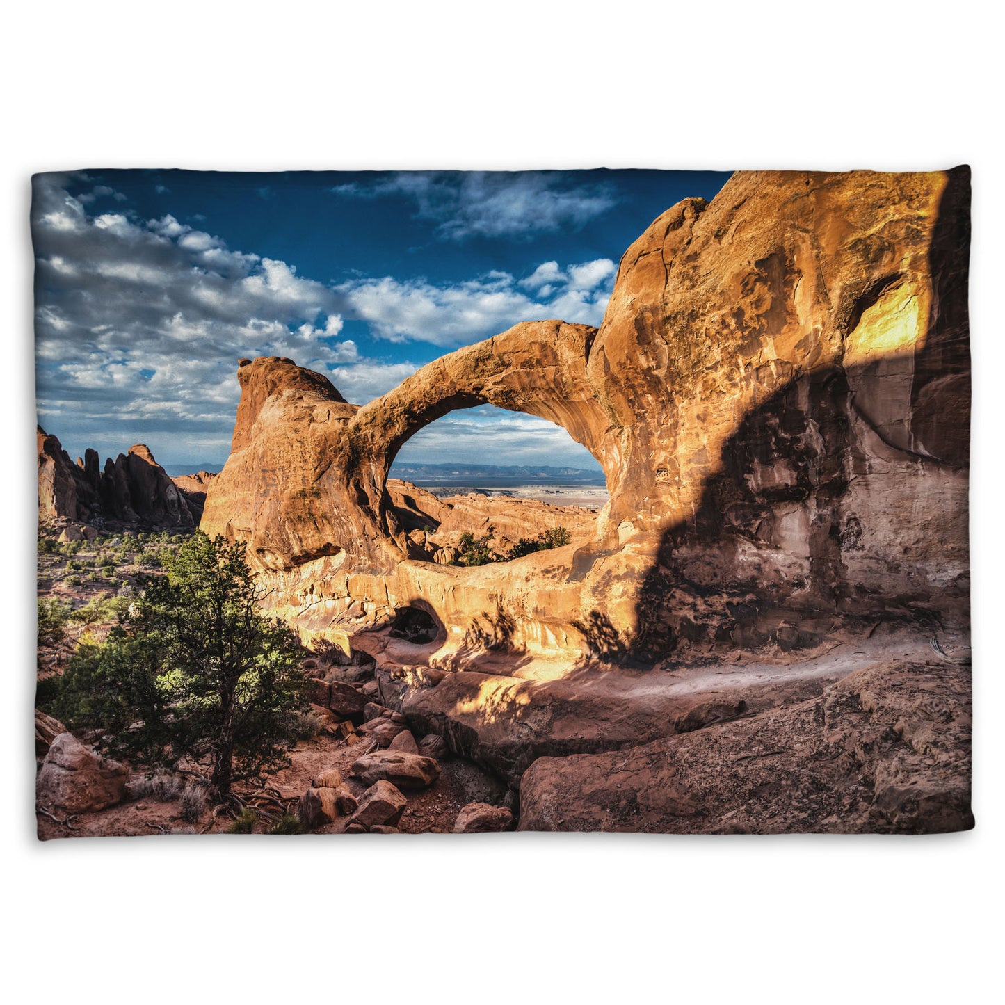 Fleece throw blanket designed with a photo of the Double O arch in the Devil's Garden at Arches National Park, Utah. The rocky arch is set against a bright blue sky.