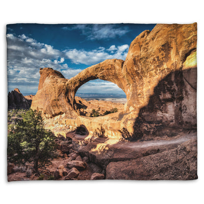 Fleece throw blanket designed with a photo of the Double O arch in the Devil's Garden at Arches National Park, Utah. The rocky arch is set against a bright blue sky.
