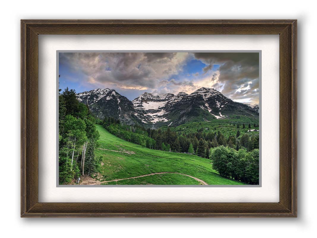 Photo of snowcapped mountains and rolling green hills and forestry, at the Sundance Ski Resort in Utah. Printed on paper, matted, and framed.