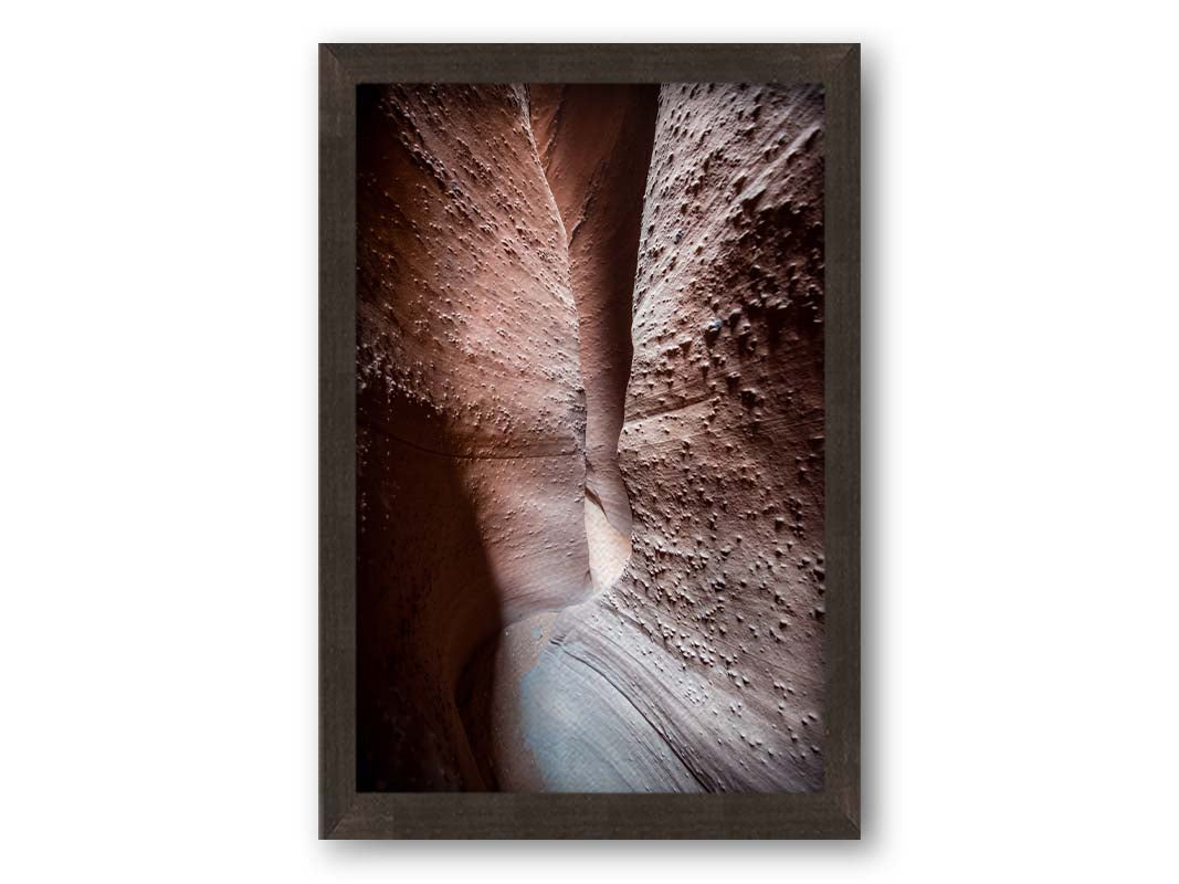 A photo of the slot canyon called Spooky near Escalante, Utah. It features a narrow crevice of lrough and smooth layers of stone. Printed on canvas and framed.