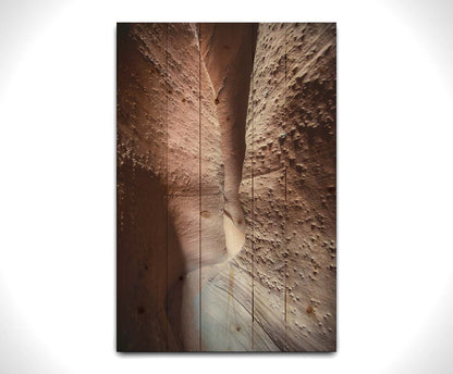 A photo of the slot canyon called Spooky near Escalante, Utah. It features a narrow crevice of lrough and smooth layers of stone. Printed on a wood pallet.