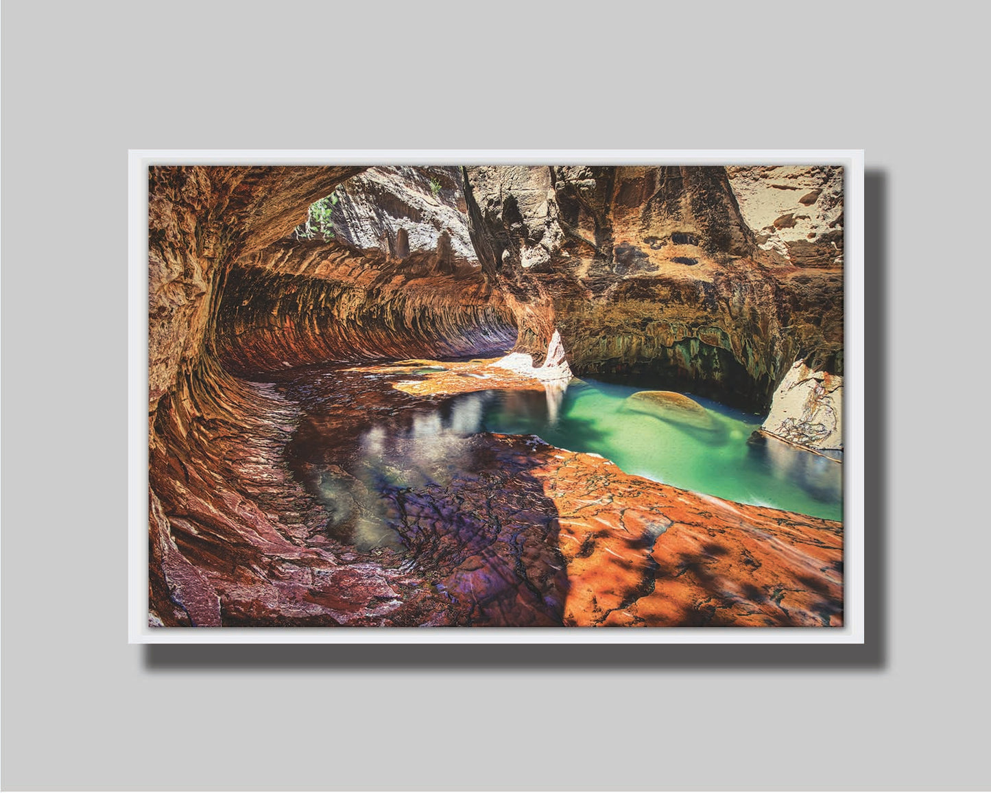 A photo from inside The Subway, or Left Fork of North Creek, at Zion National Park in Utah. It features a canyon of orange and red stone with a vibrant pool of green waters. Printed on canvas in a float frame.