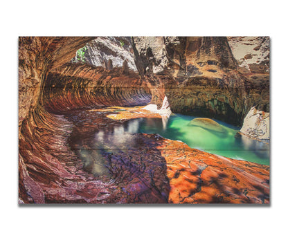 A photo from inside The Subway, or Left Fork of North Creek, at Zion National Park in Utah. It features a canyon of orange and red stone with a vibrant pool of green waters. Printed on a box board.