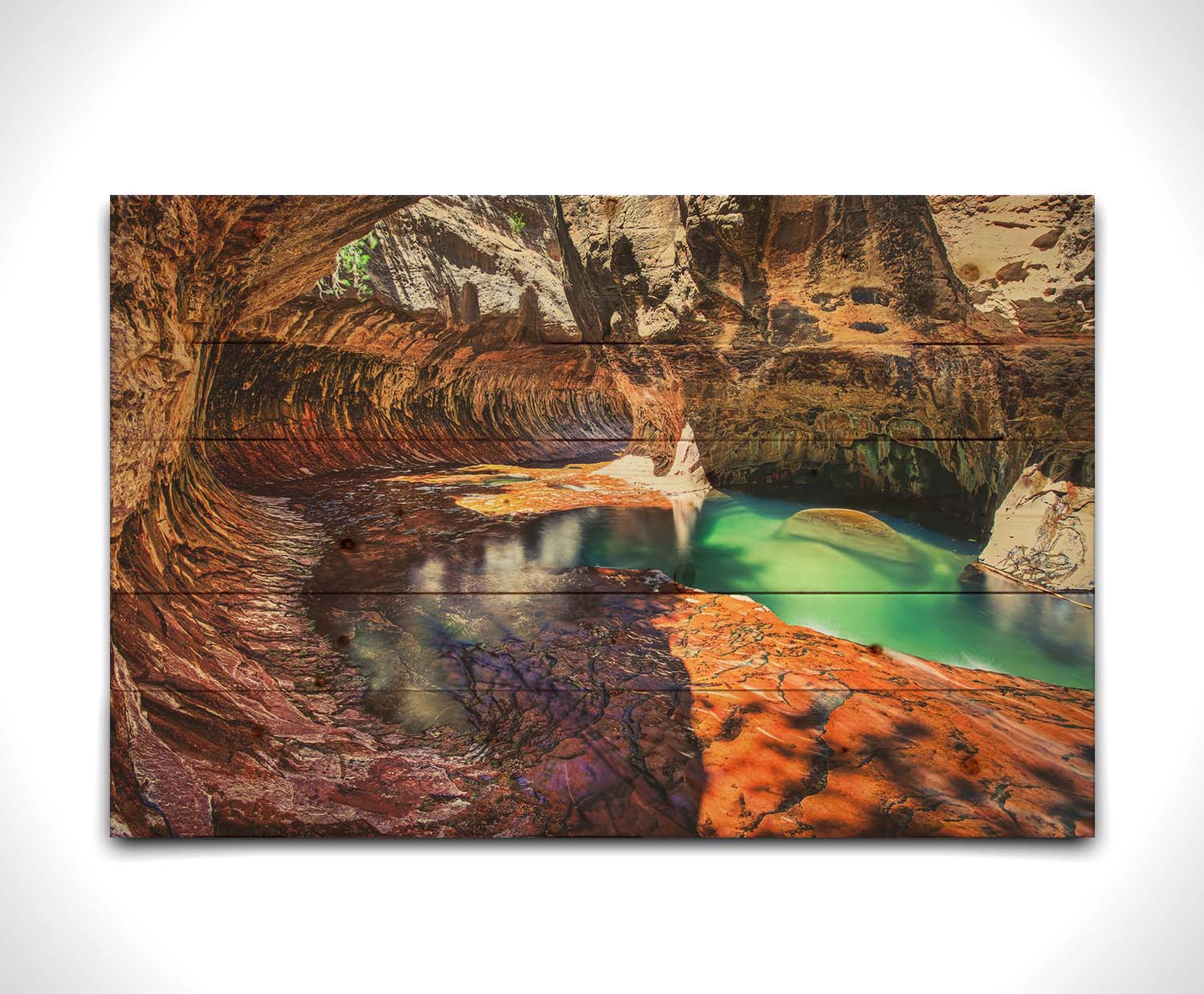 A photo from inside The Subway, or Left Fork of North Creek, at Zion National Park in Utah. It features a canyon of orange and red stone with a vibrant pool of green waters. Printed on a wood pallet.