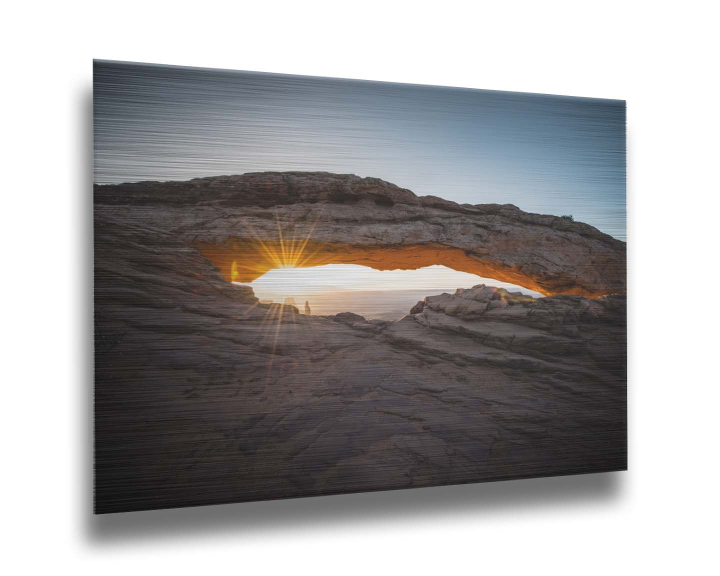 Photo of a stone arch from a national park in Utah. The sunrise site just between the horizon and the underside of the arch, creating a beautiful orange highlight to the underside of the stone structure. Printed on metal.