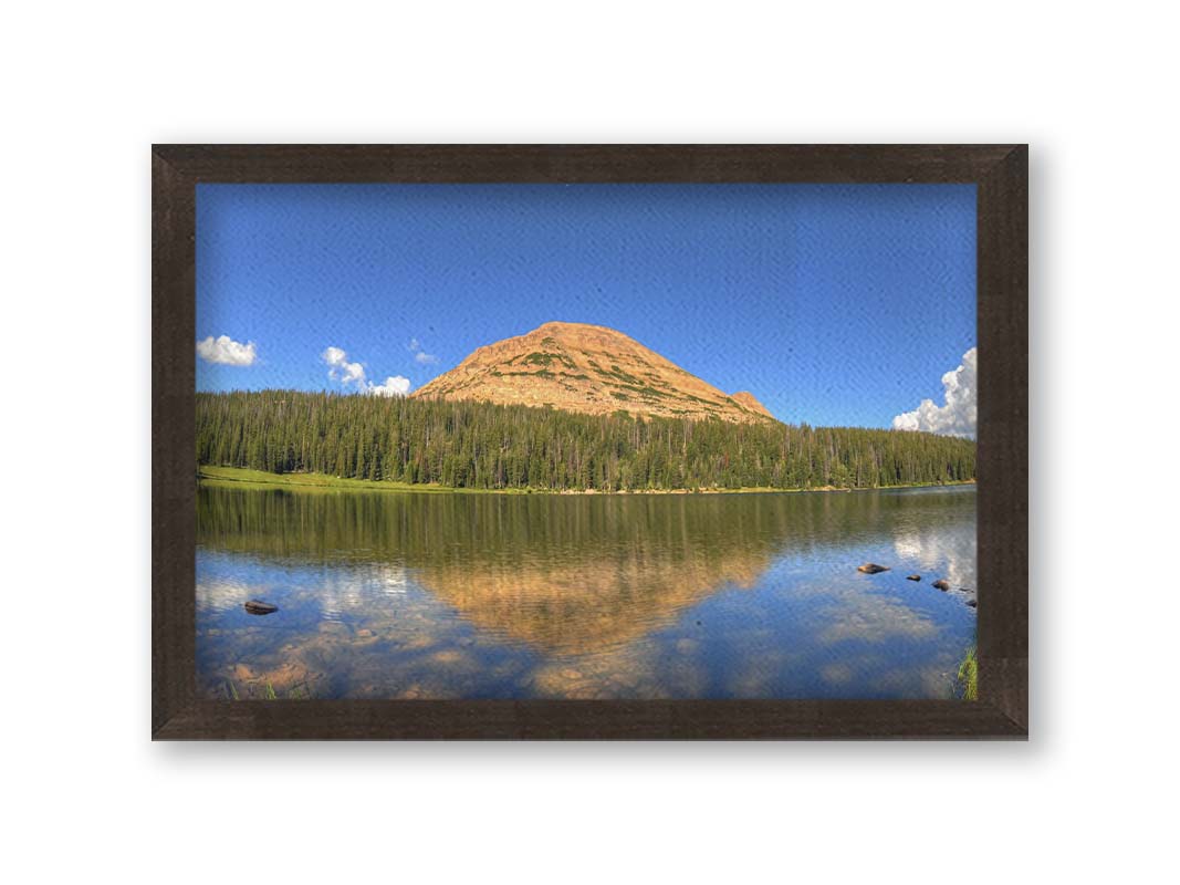 Photo of Mirror Lake in Utah. A mountain, forest, blue sky, and fluffy clouds are reflected on the lakewater. Printed on canvas and framed.