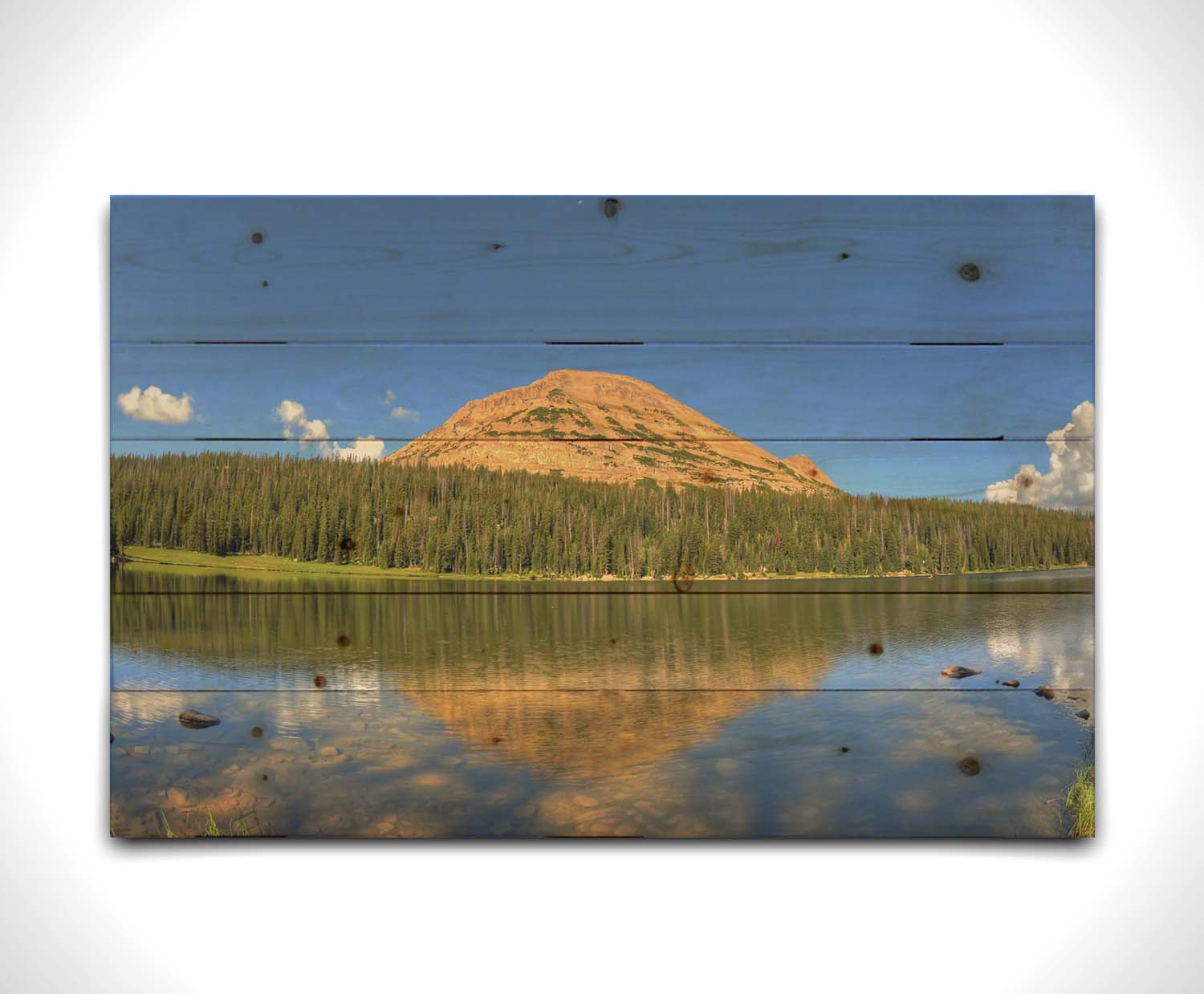 Photo of Mirror Lake in Utah. A mountain, forest, blue sky, and fluffy clouds are reflected on the lakewater. Printed on a wood pallet.