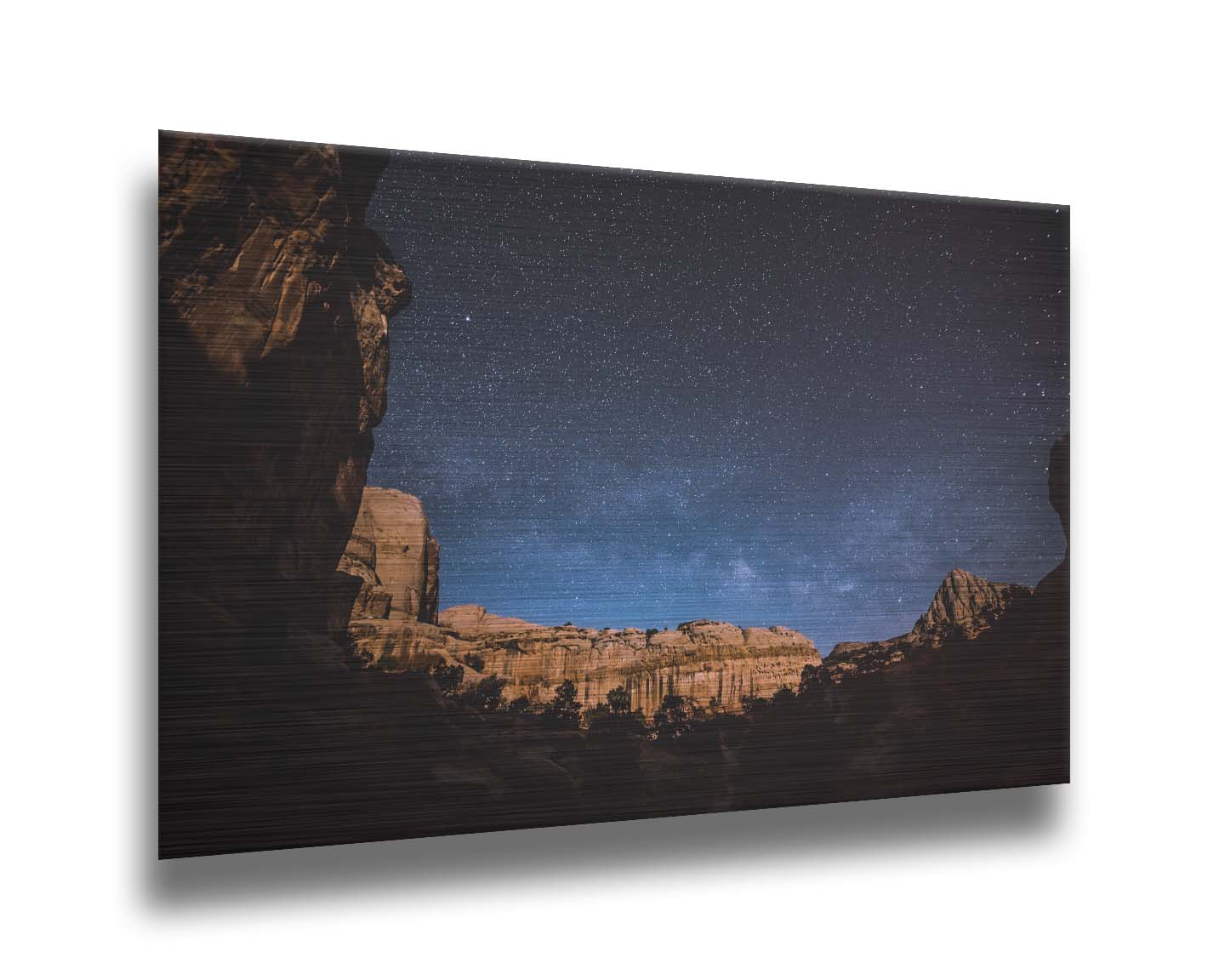 A photo of a clear, starry night sky from the Capitol Reef National Park. The stony plateaus encircle the view of the stars. Printed on metal.